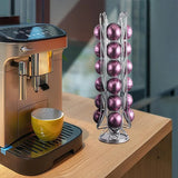 Silver coffee pod holder with purple pods next to yellow cup and espresso machine on wooden counter