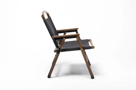 Side view of a black fabric and wooden outdoor folding chair with armrests on white background