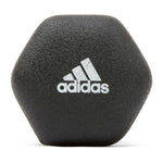 Black Adidas hexagonal dumbbell with white Adidas logo on textured surface