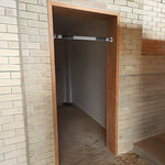 Adjustable metal pull-up bar installed in doorway with brick walls and wooden frame