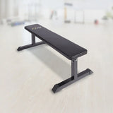 Flat weight bench with black padded seat in a bright gym setting