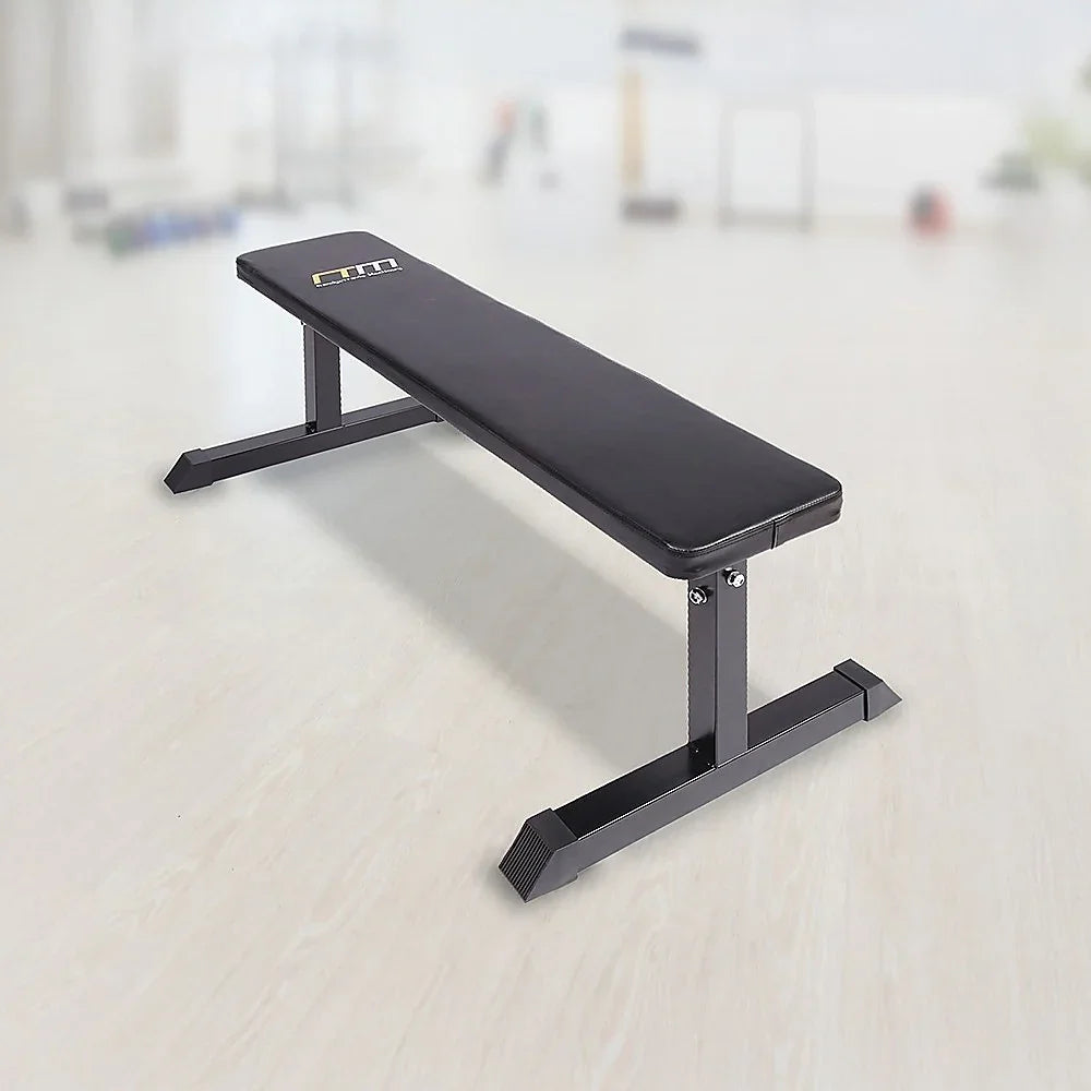 Flat weight bench with black padded seat in a bright gym setting