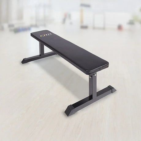 Flat weight bench with black padded seat in a bright gym setting