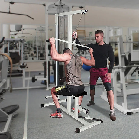 Man using lat pulldown machine in gym with trainer spotting, strength training equipment