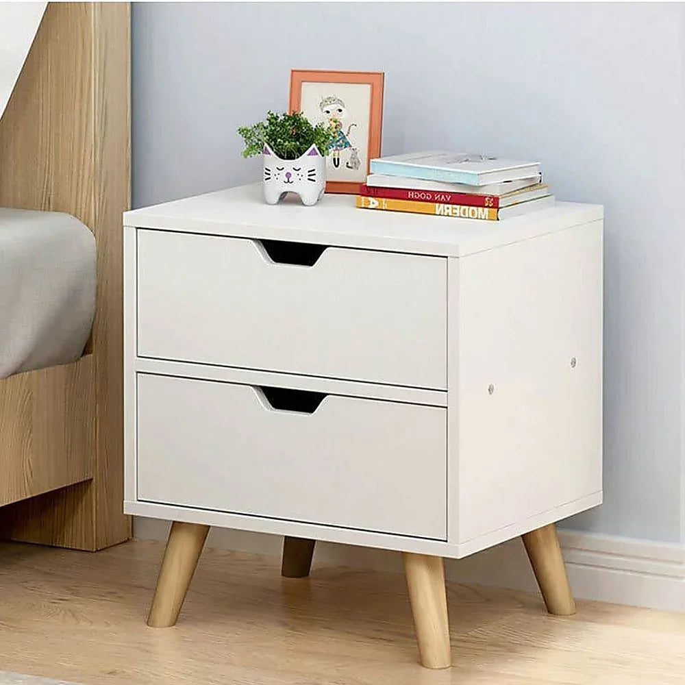 Modern white nightstand with two drawers, wood legs, books, plant, and photo frame on top