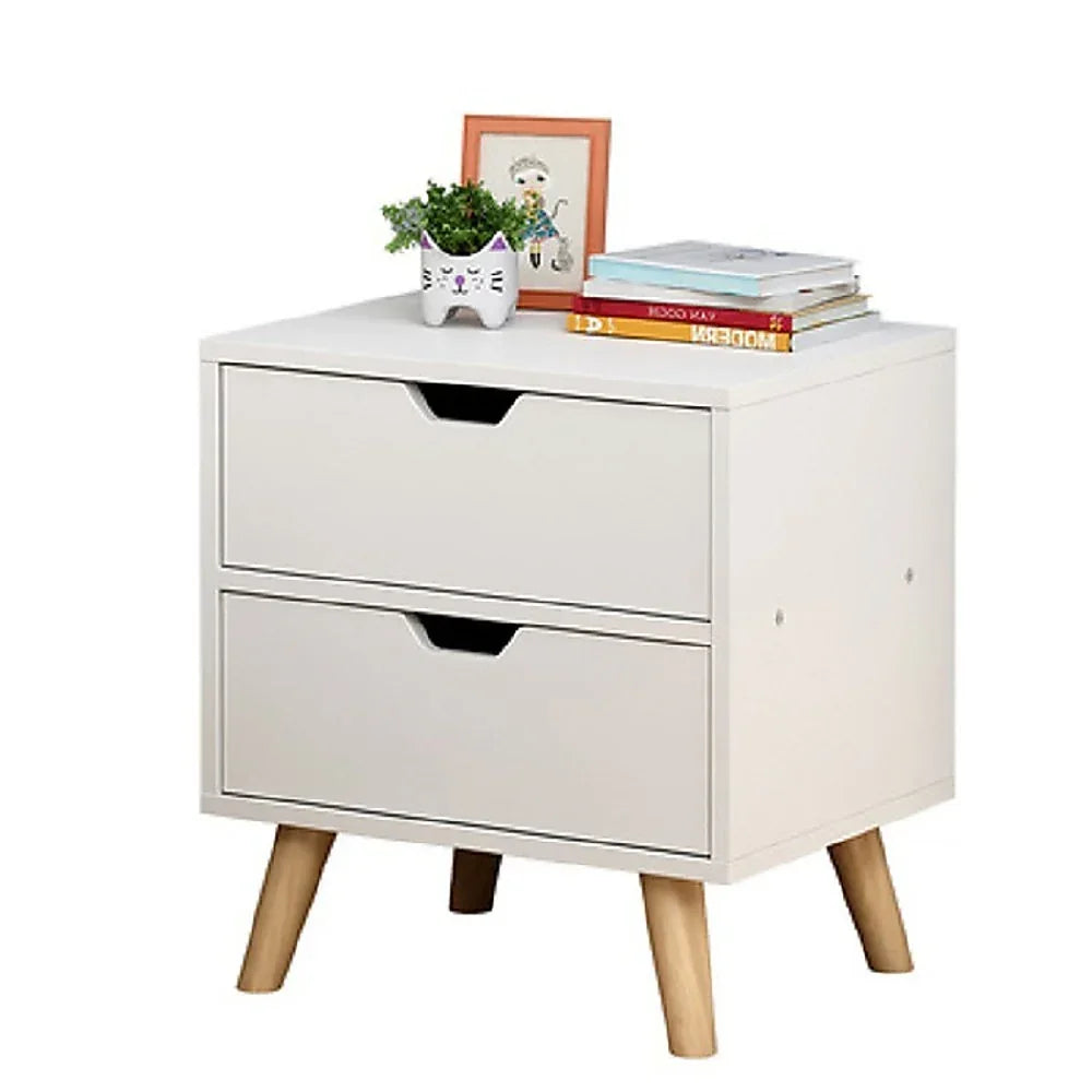Modern white nightstand with two drawers, wooden legs, books, a cat planter, and framed art