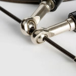 Close-up of silver metal clips attached to black cables on a white surface