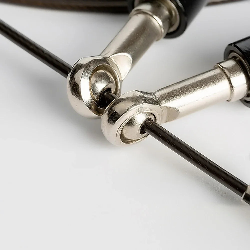 Close-up of silver metal clips attached to black cables on a white surface