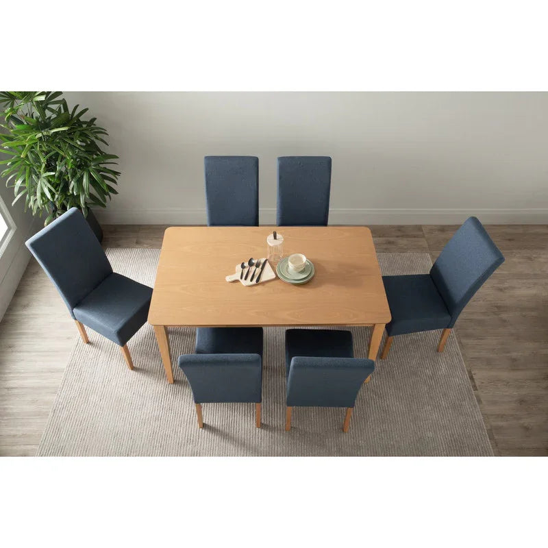 Modern dining room with light wood table, six blue chairs, dishes, and plant on rug