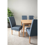 Modern dining room with wooden table, four blue upholstered chairs, potted plant