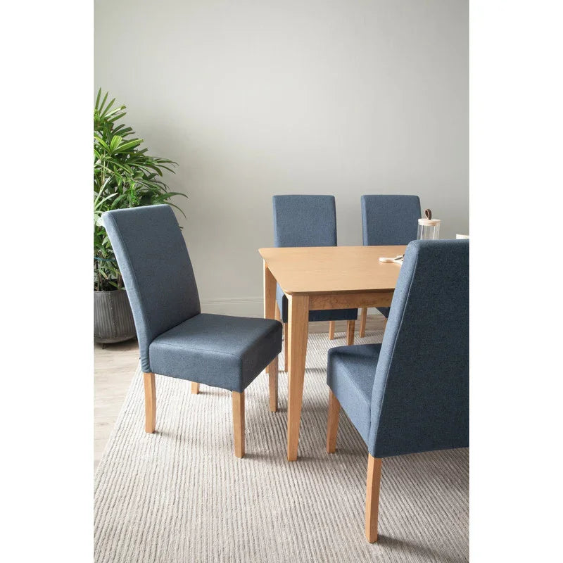 Modern dining room with wooden table, four blue upholstered chairs, potted plant