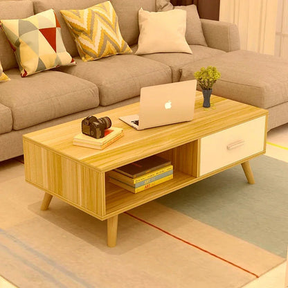 Modern wooden coffee table with books, laptop, camera and vase in a cozy living room