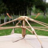 Close-up of brown outdoor umbrella mechanism showing open ribs and fabric canopy with green trees background