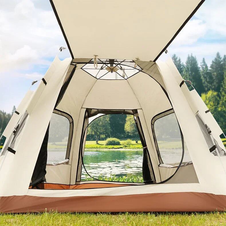 Interior view of a spacious beige camping tent with mesh windows set up on green grass by a lake and forest