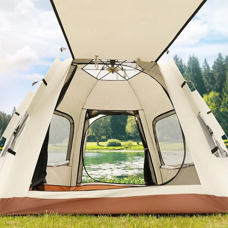 Interior view of a spacious beige camping tent with mesh windows set up on green grass by a lake and forest