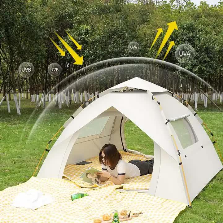 White UV protective camping tent with a woman reading inside in a green park surrounded by trees