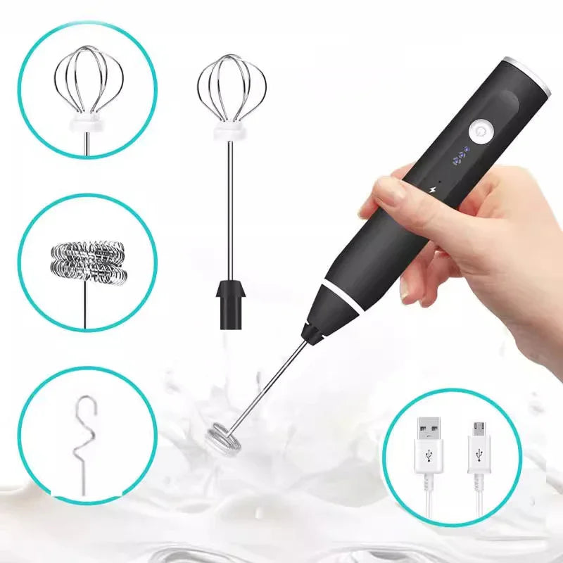 Hand holding black electric milk frother with three interchangeable whisk heads and USB charging cable