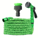 Expandable green garden hose with adjustable spray nozzle and black connector fitting
