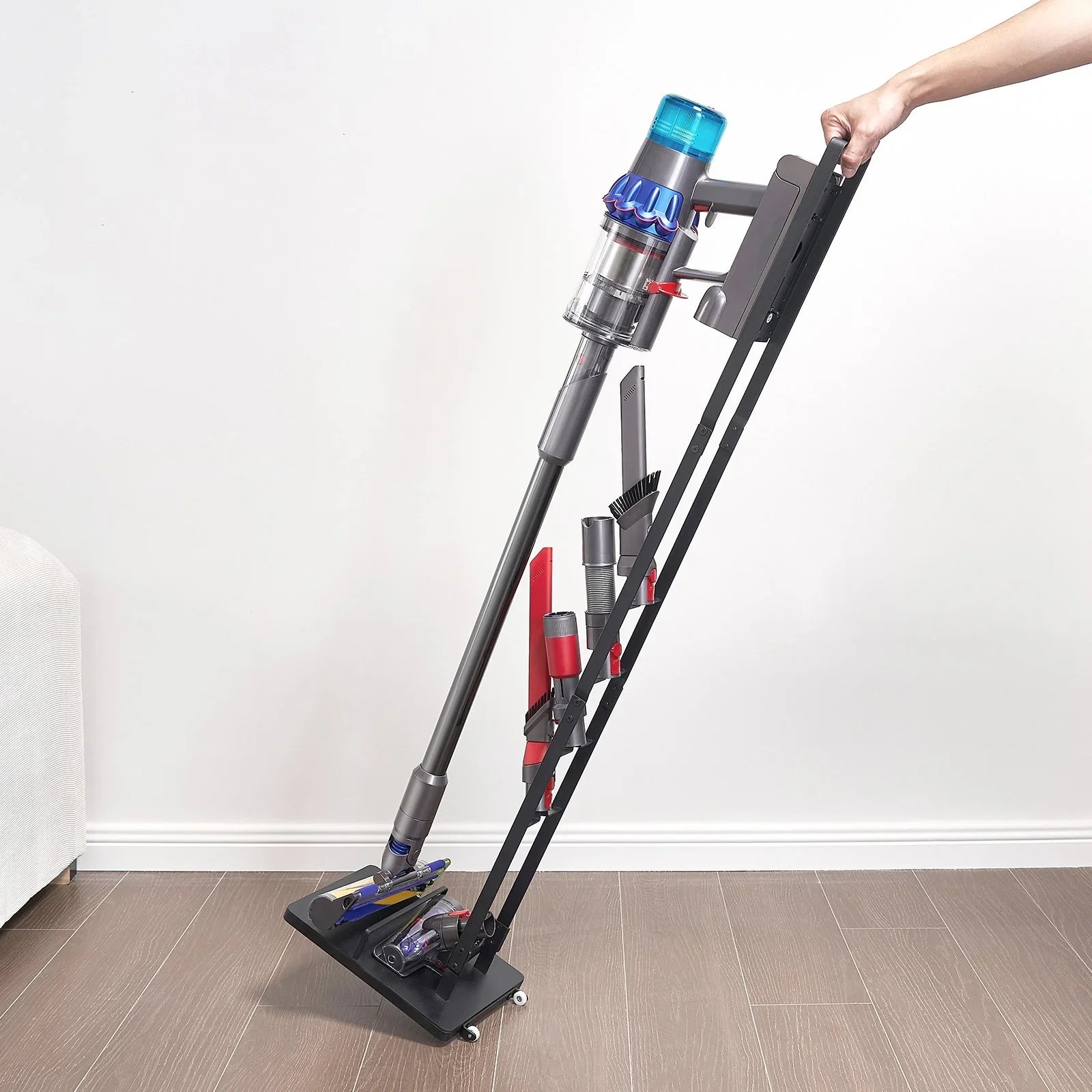 Cordless vacuum cleaner with multiple attachments on a black rolling stand indoors