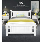 Modern white wooden bed with gray and yellow bedding in a stylish bedroom with nightstands and lamps