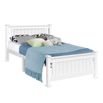 White wooden bed frame with vertical slats, blue blanket, and multiple decorative pillows