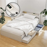 White platform bed with under-bed storage drawers and built-in charging ports in a bright bedroom