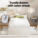 White modern single bed with green pillow and trundle drawers with castor wheels in bright bedroom