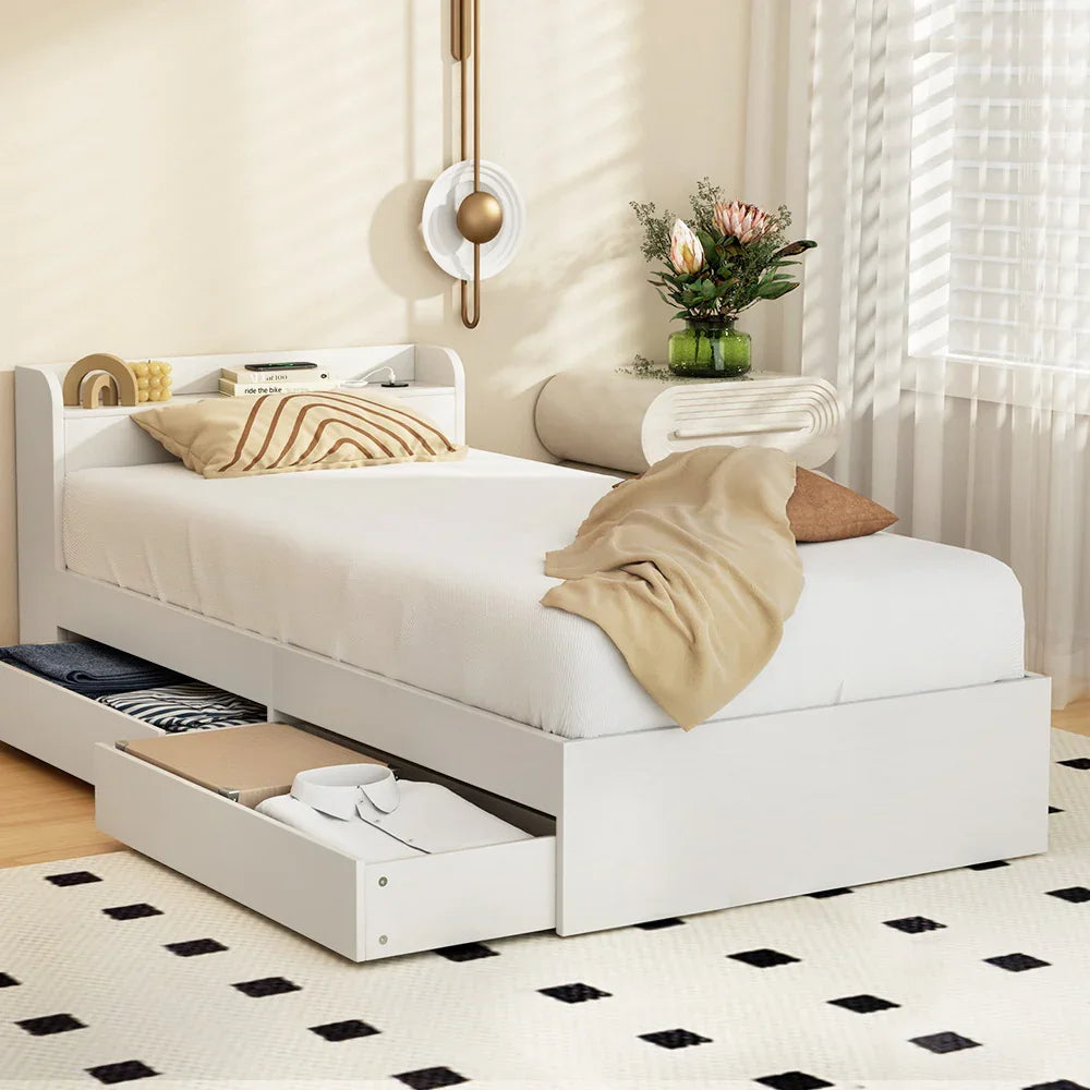 Modern white single bed with storage drawers, beige bedding, and decorative wall light in cozy bedroom