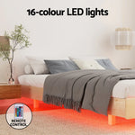 Modern bedroom with wooden bed featuring red 16-color LED lights underbed and remote control